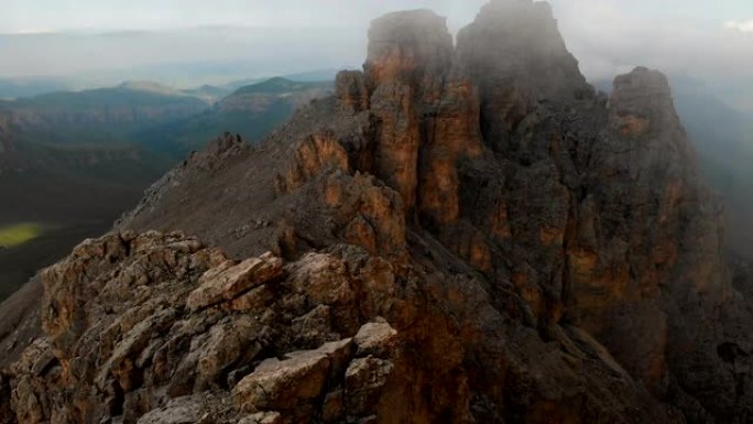 日落时无人机飞越尖锐的岩石露头的鸟瞰图。用于极端登山的陡峭的岩层山。飞行穿越旅行视频