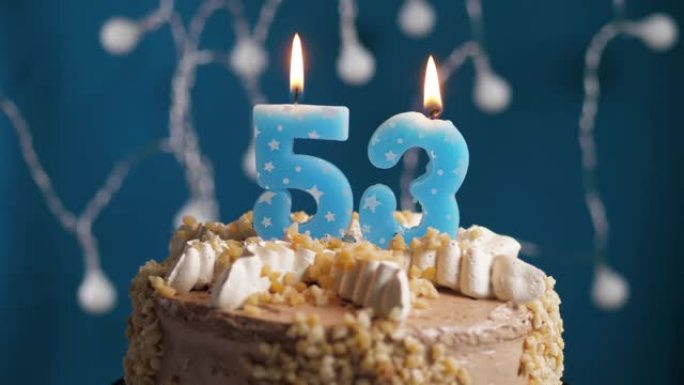 蓝色背景上有53号蜡烛的生日蛋糕。蜡烛吹灭了。慢动作和特写视图