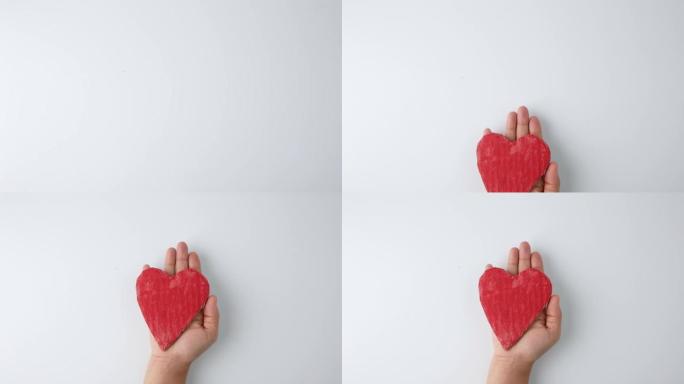 放在手上并伸出的红色心形纸板，孤立在白色背景上。爱情和情人节的概念。