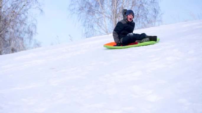 一个孩子在雪山上骑车玩耍。慢动作。白雪皑皑的冬季景观。户外运动