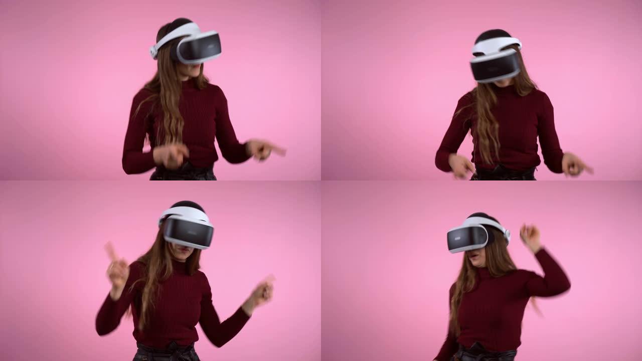 虚拟现实眼镜耳机中快乐年轻女孩的粉红色背景上的移动手势。工程开发，电子互动创新。女性在增强现实中玩游