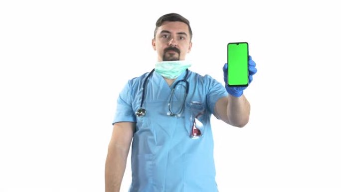 带防护面罩的年轻男医生肖像手持智能手机，白底色键绿屏