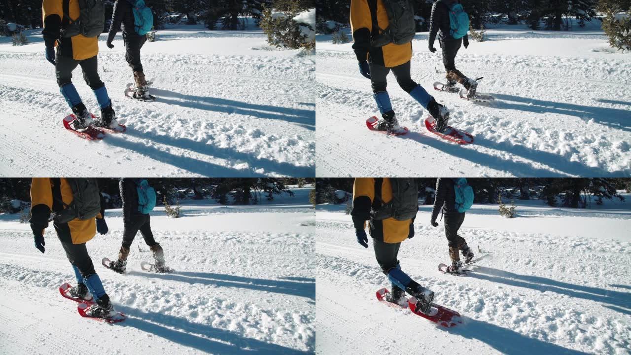 慢动作手持侧角跟随成年徒步旅行者从相机走到阳光下的拍摄雪鞋在户外深雪中行走