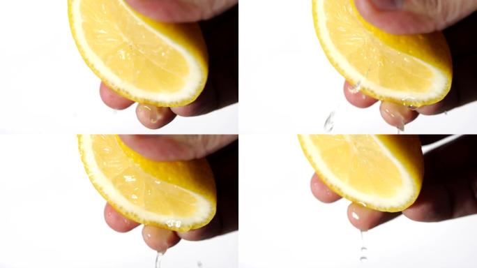 用手在白色背景上慢动作挤压新鲜柠檬。柠檬汁从果肉和滴水中排出。