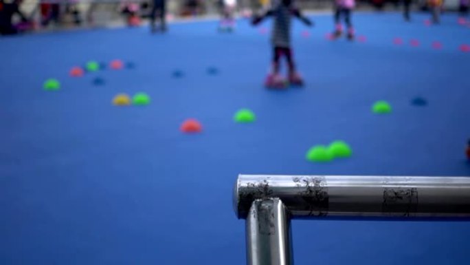 公园里孩子们直排轮滑的教学。重点是金属栏杆。背景模糊了。主题在右边。
