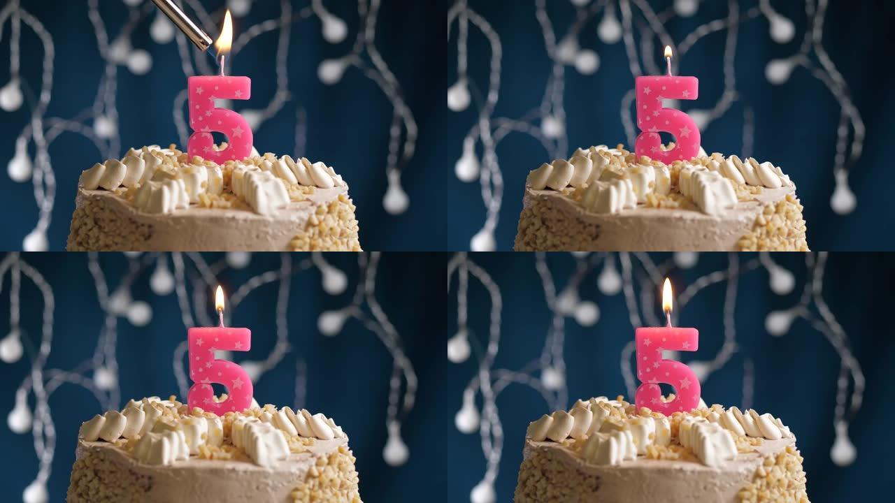 蓝色背景上有5个粉色蜡烛的生日蛋糕。蜡烛着火了。慢动作和特写视图