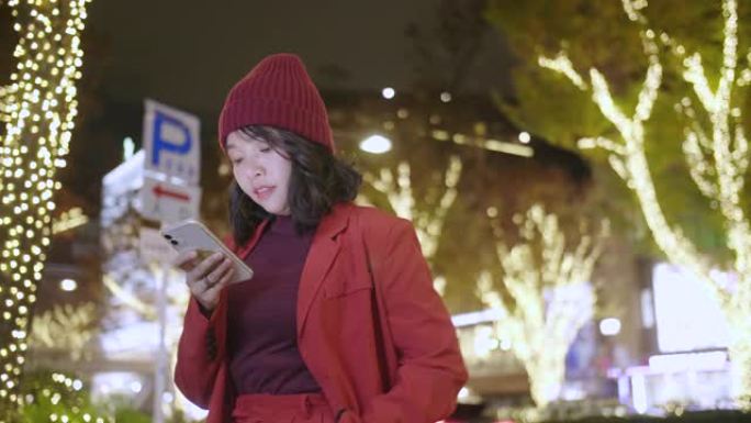 亚洲女孩在城市等待时检查她的手机。