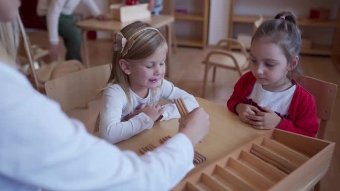 学龄前老师向女孩讲解如何在幼儿园玩益智玩具