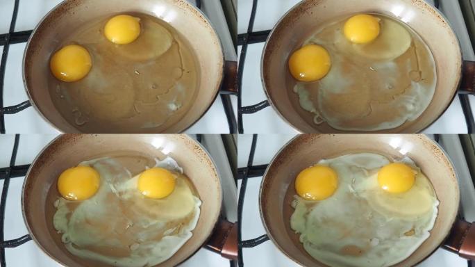 两个鸡蛋在煎锅里用油油炸。在家庭厨房的煤气炉上煮鸡蛋。