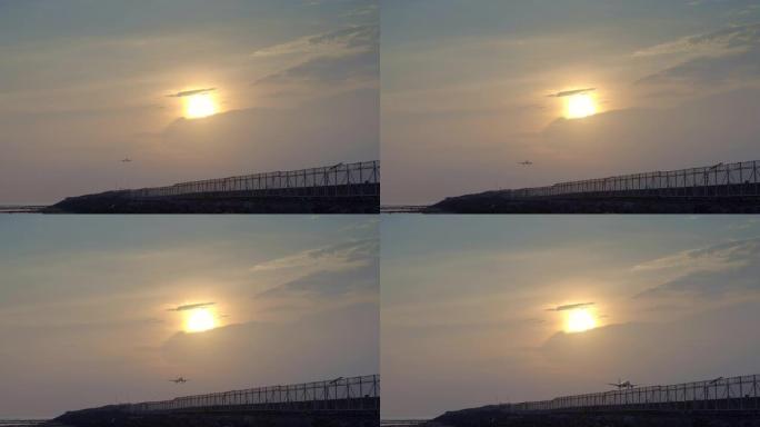 民用飞机在黄色的日落下降落在热带海滩附近的跑道上，太阳在后面