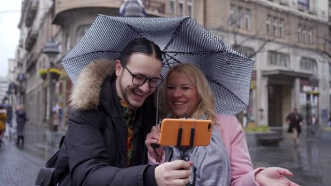 旅行视频记录器在下雨时在自拍杆上记录手机上的vlog