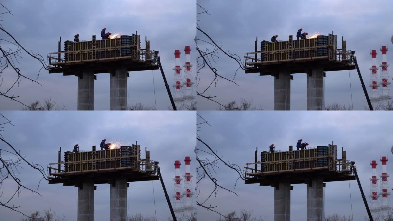 工人的剪影-在立柱上工作的安装人员，正在建造的汽车立交桥的支架