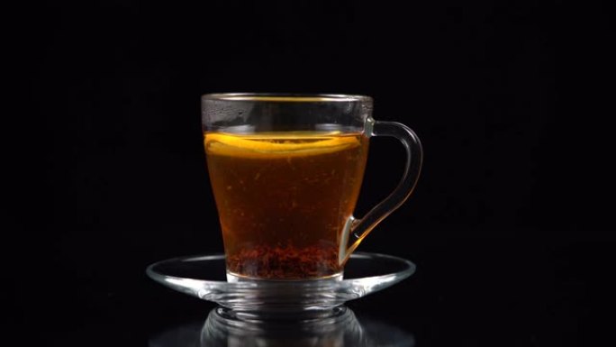 在玻璃茶杯中蘸有热茶的一片柠檬漂浮在水面上。