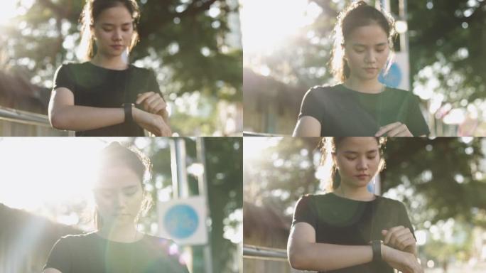 亚洲女运动员在智能手表上检查心率。日落时在街上慢跑锻炼生活方式。健康的生活方式。