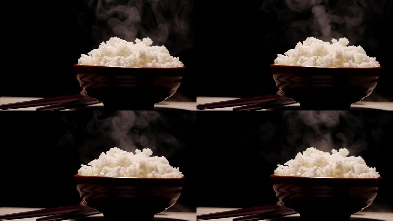 慢动作在黑色背景的碗里用蒸汽煮熟的米饭。热蒸米饭的镜头