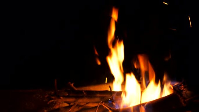 明亮的火焰从黑色背景上的mangal燃烧的木片和木炭中升起。晚上烧烤炉烧柴和煤。温暖和宁静的概念。多