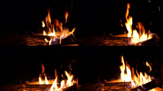 明亮的火焰从黑色背景上的mangal燃烧的木片和木炭中升起。晚上烧烤炉烧柴和煤。温暖和宁静的概念。多