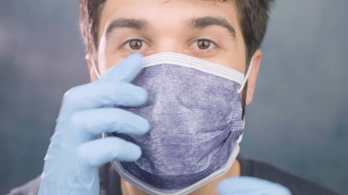 男子肖像戴卫生防护口罩和手套防止病毒