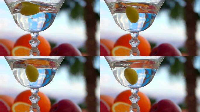 一颗绿橄榄正在落入装有马提尼酒的玻璃杯中