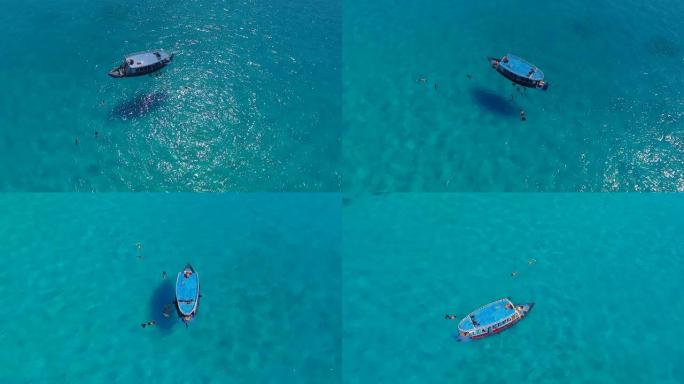 人们在蓝色船上清澈的蓝色透明绿松石海水中一起浮潜和游泳。马尔代夫。鸟瞰图。海洋夏季热带假期的概念。