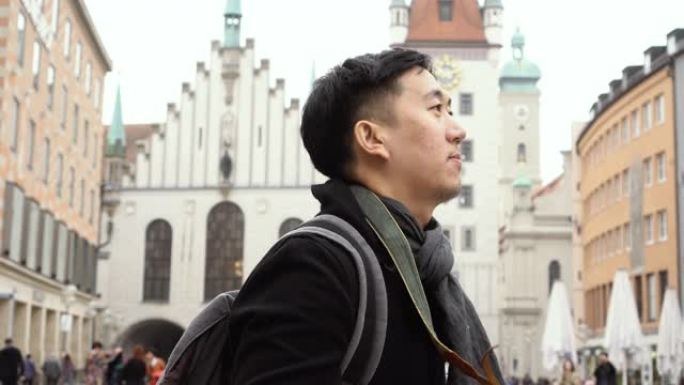欧洲市中心的年轻亚洲旅行背包客。男子在德国慕尼黑玛利亚广场拍照