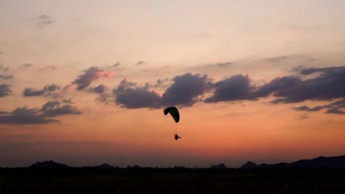 在泰国华富里的Khao Jeen Lae山上日落时，滑翔伞在空中飞行的慢动作