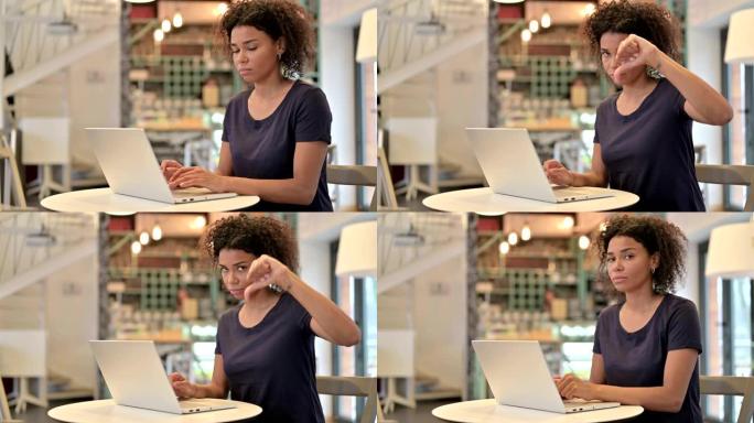 年轻的非洲妇女，笔记本电脑显示拇指朝下