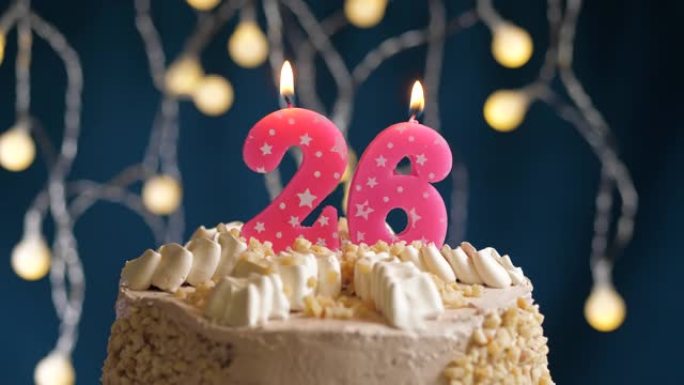 蓝色背景上有26个粉色蜡烛的生日蛋糕。蜡烛吹灭了。慢动作和特写视图