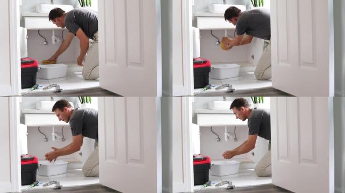 家里的男人从浴室漏水的管道中清理水