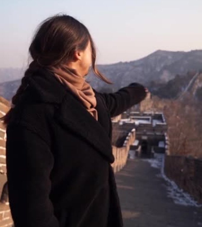 幸福的女人走在中国的长城上，冬天日落时从八达岭区的守望台下来。垂直视频