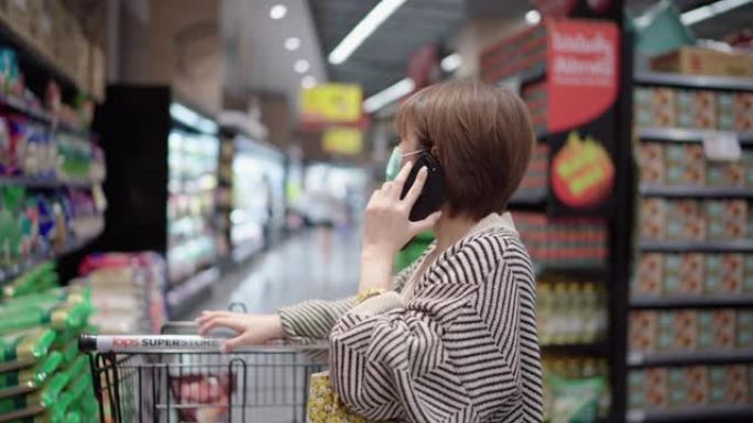 在杂货店，超市使用智能手机的亚洲时髦女性