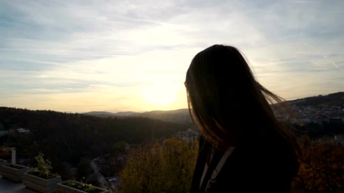 美丽的女孩凝视着保加利亚Veliko Tarnovo风景秀丽的山丘上的日落云