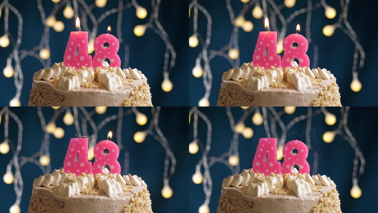 蓝色背景上有48号粉色蜡烛的生日蛋糕。蜡烛吹灭了。慢动作和特写视图