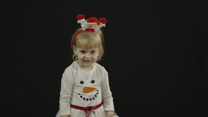 穿着雪人服装的快乐美丽女婴。圣诞节。做鬼脸，跳舞