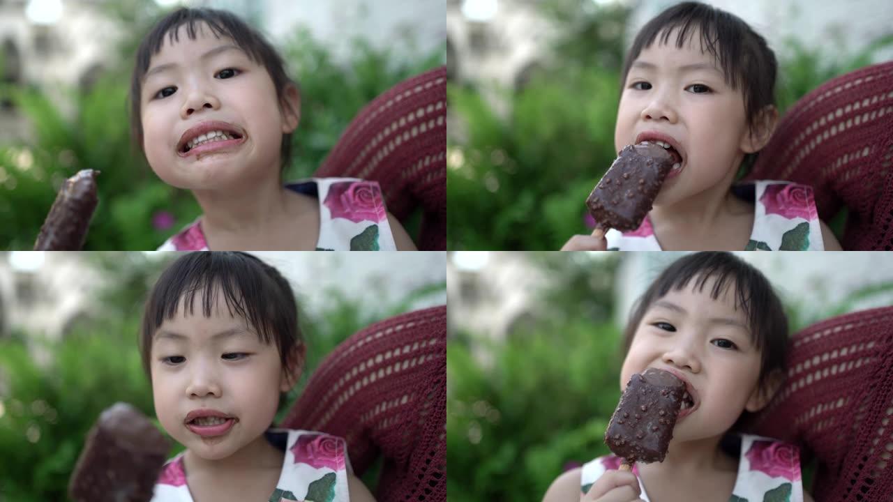 亚洲小女孩吃冰淇淋，她微笑着看着相机。孩子开心地吃冰淇淋。幸福家庭理念。手持镜头和现实生活。