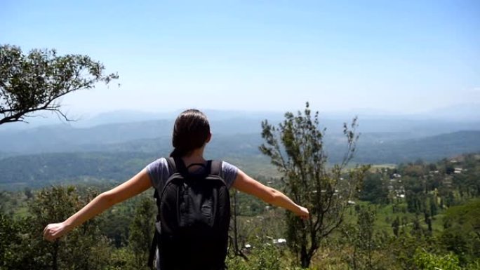 背着背包的女游客慢跑到峡谷边缘，举起手来。女徒步旅行者跑到山顶，伸出手臂。年轻女孩享受美丽如画的风景