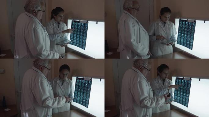 两名外科医生讨论头部的ct扫描和肩部的MRI扫描。神经外科医生团队在看病人的断层扫描时，讨论了他们将