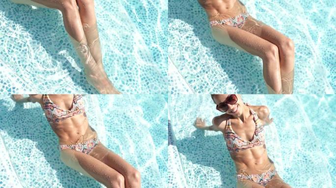 慢动作多莉拍摄的黑色太阳镜中的漂亮女孩，惊人的超薄fitnes身体在游泳池放松，享受温暖的夏日