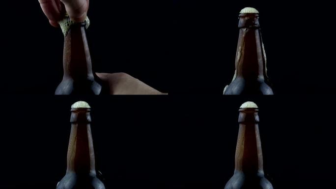 男人的手摇晃一瓶啤酒，然后打开它。啤酒泡沫从盖子下面逸出。