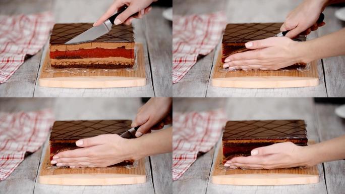 糕点厨师用樱桃做巧克力蛋糕。女人的手切开了蛋糕的边缘。
