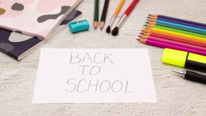 返回学校标题出现在带有学校用品的桌子上的白皮书上-停止动作