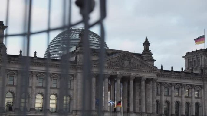 慢镜头:阴天的德国柏林，德国国旗迎风飘扬，背景是联邦议会大厦