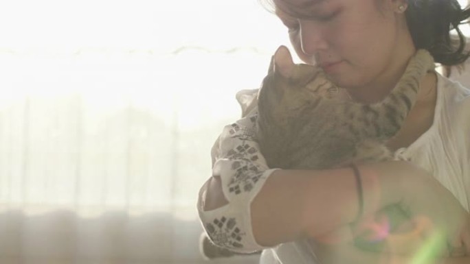 女人拥抱和亲吻她的宠物小猫的肖像。