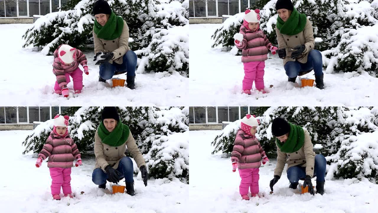 有女儿的女人扔雪球。幸福的家庭女孩。降雪