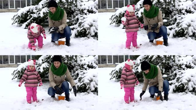 有女儿的女人扔雪球。幸福的家庭女孩。降雪