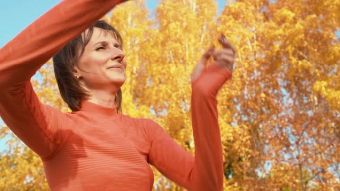 快乐的女人在秋季公园跳舞。美丽的女人在橘子树背景公园的户外锻炼中训练舞蹈。健身女子训练城市公园的舞蹈