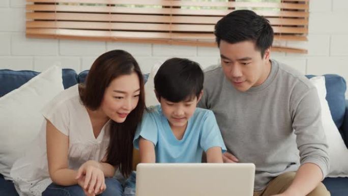 幸福的家庭在家里一起使用笔记本电脑。他们一起用电脑看电影或研究信息。家庭、技术和生活方式概念。