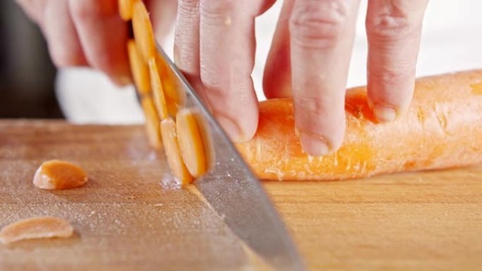 厨师刀切成胡萝卜的慢动作特写