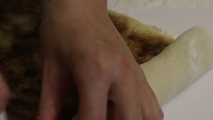 一个女人卷面团做朱砂。近距离拍摄，肉桂和糖可见。