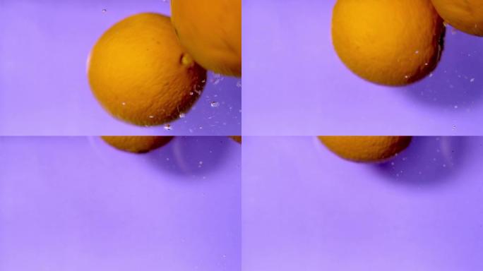 橘子在水中掉落和旋转的特写慢动作视频